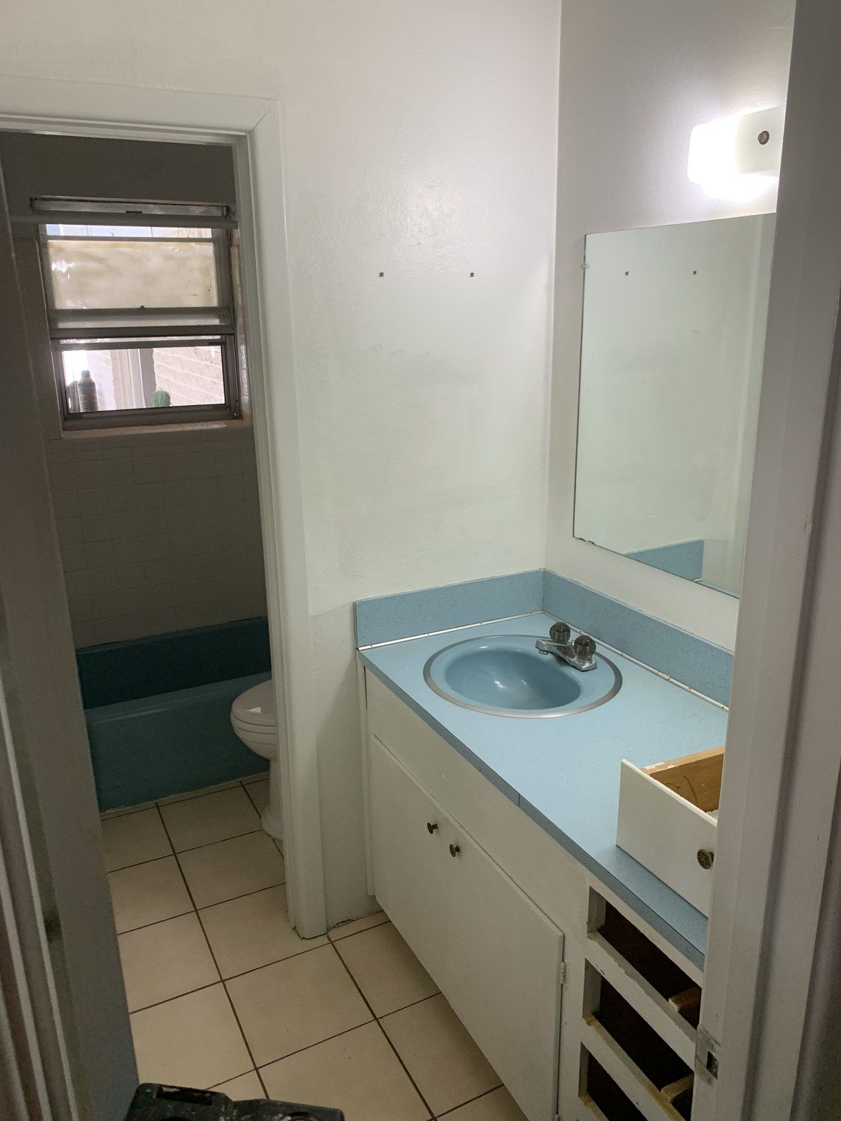 Bathroom before the remodel, with a blue laminate counter, blue sink and an old blue tub