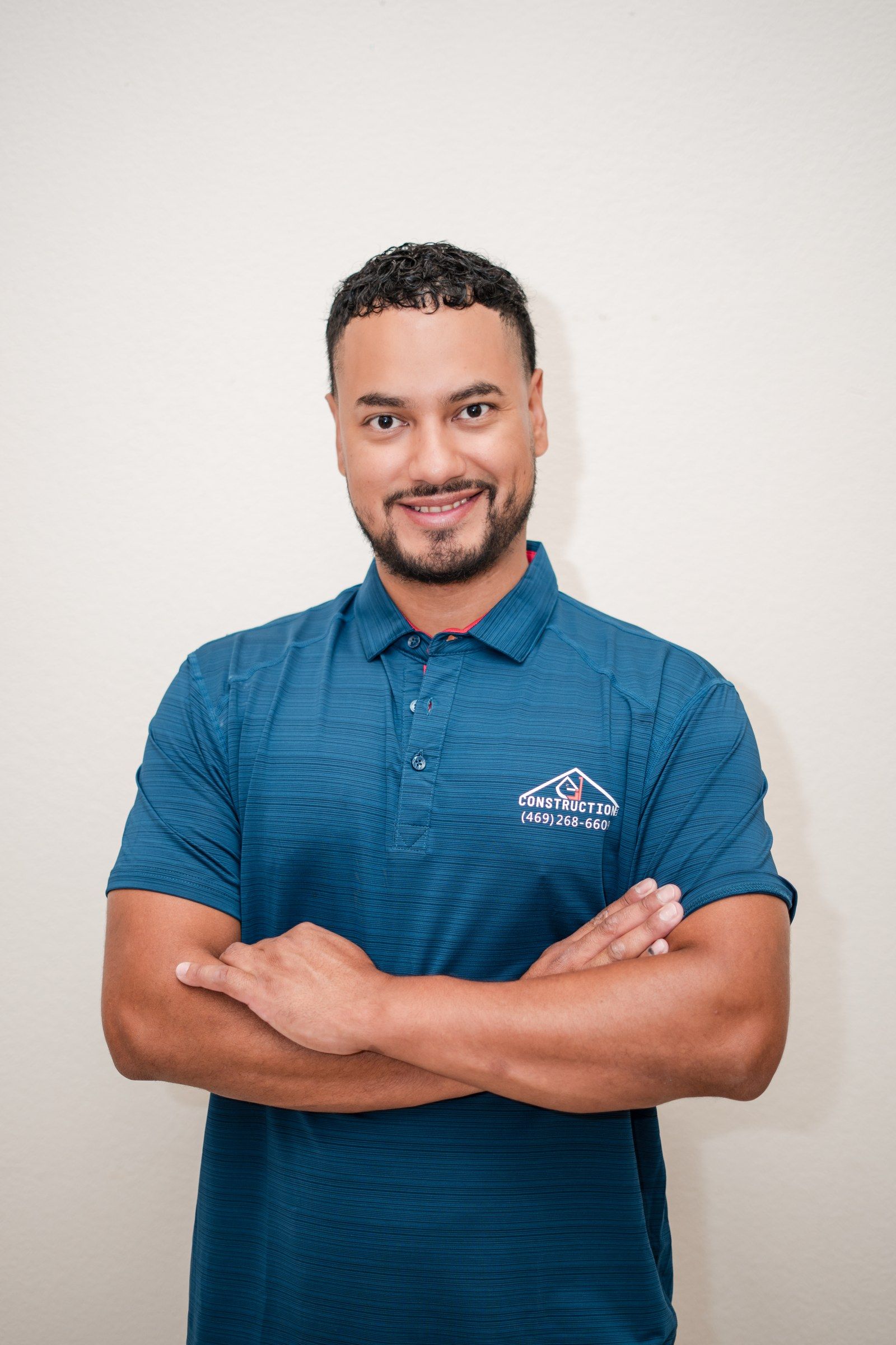 Estiven “Steven” Quiroz, owner of EJ1 Construction, in a navy company polo with arms crossed