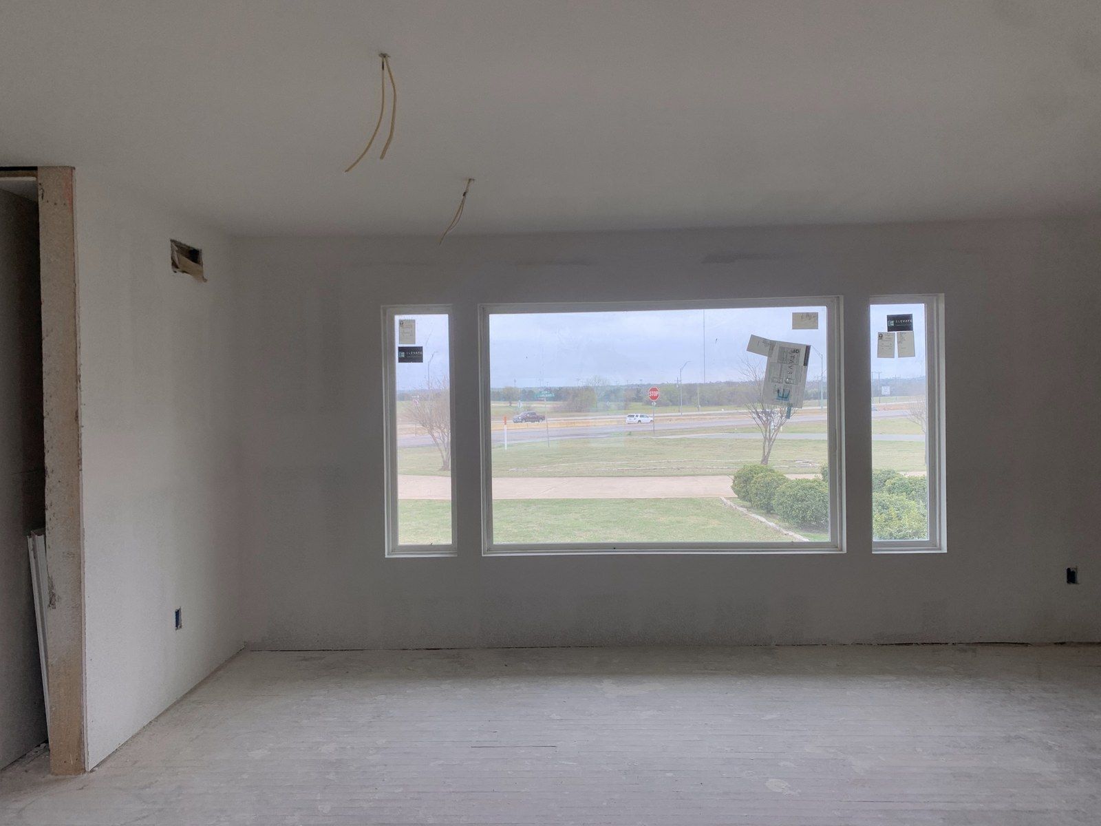 New room with a large picture window and finished drywall