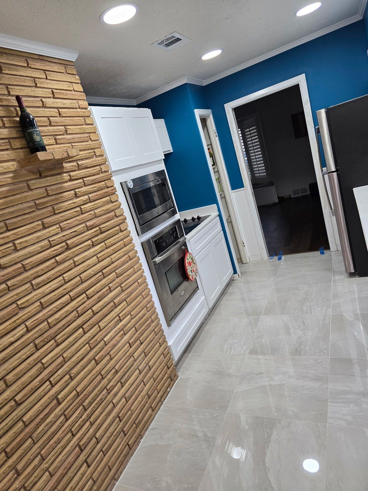 Kitchen with white shaker cabinets, double wall oven and a blue accent wall