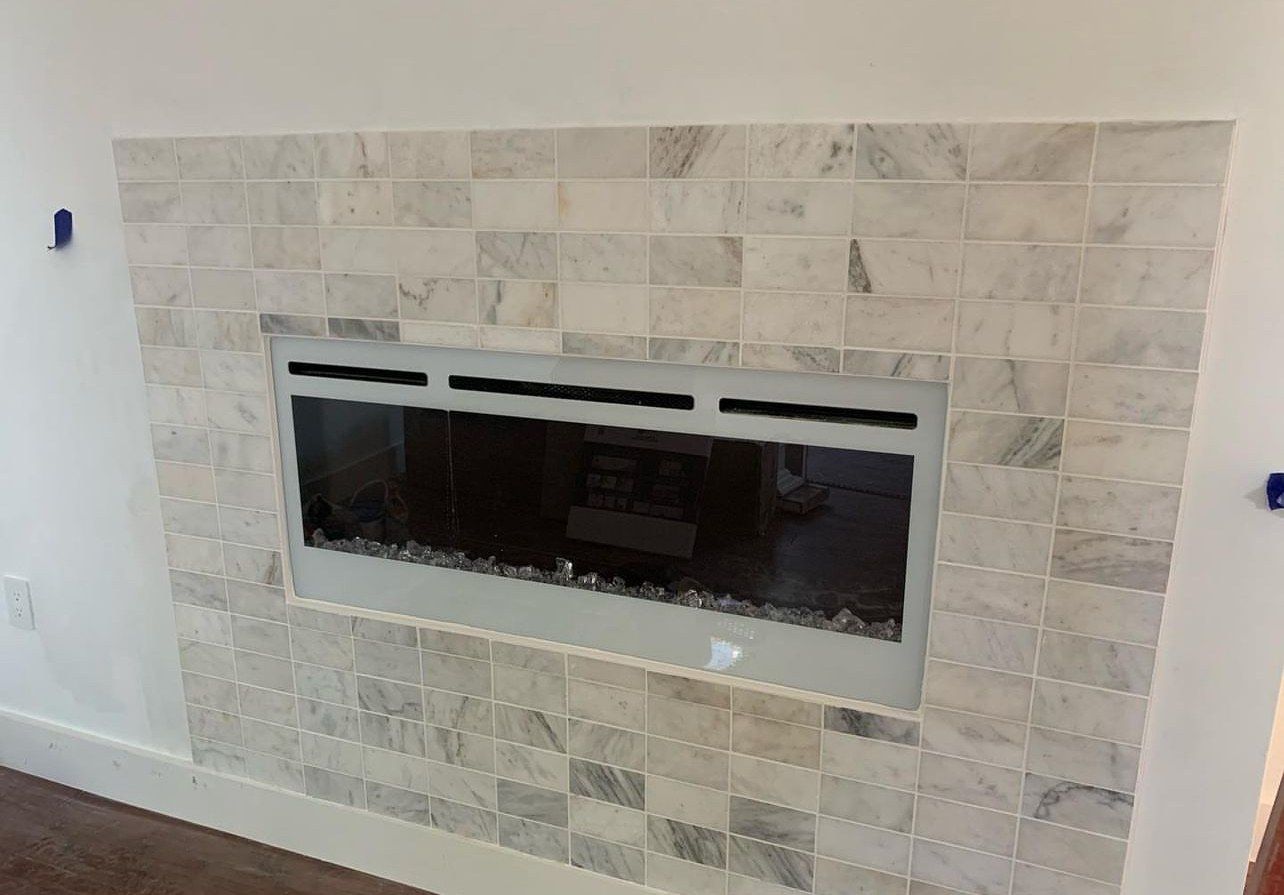 Linear electric fireplace set in a marble subway-tile surround