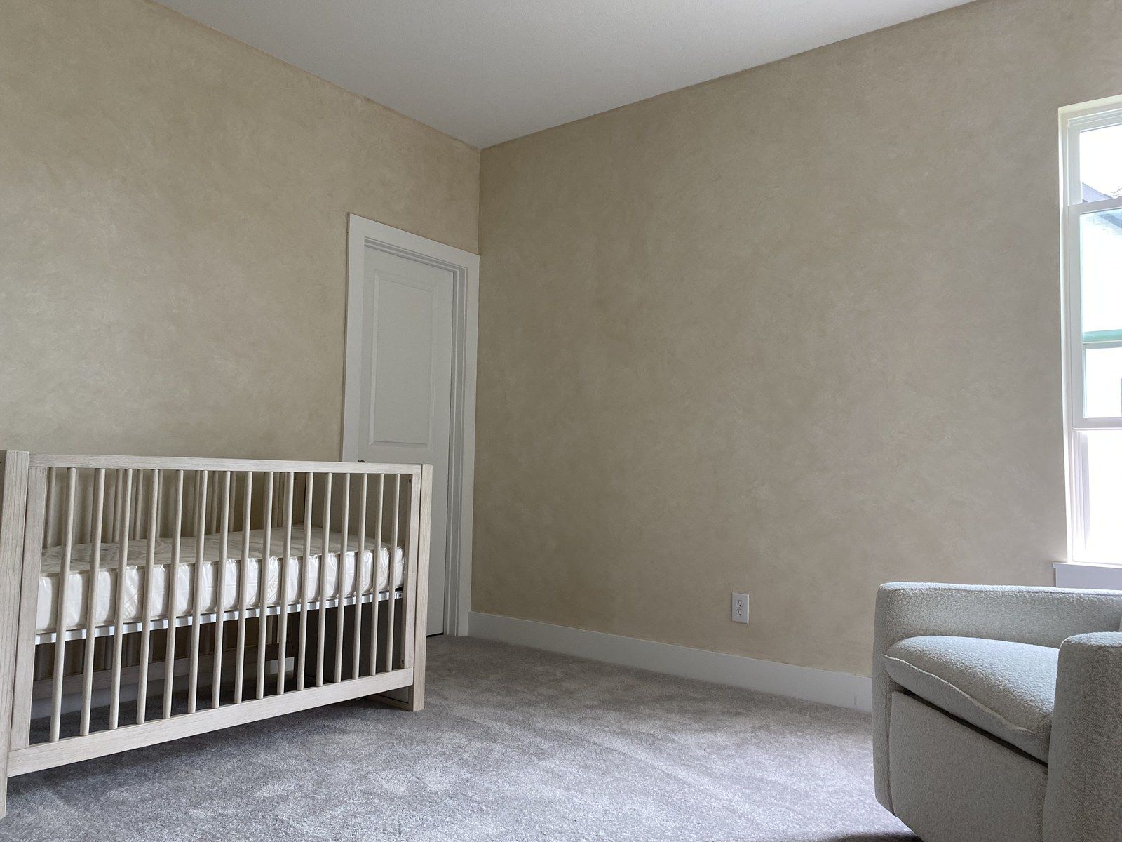 Nursery with a soft lime-wash wall finish and new carpet