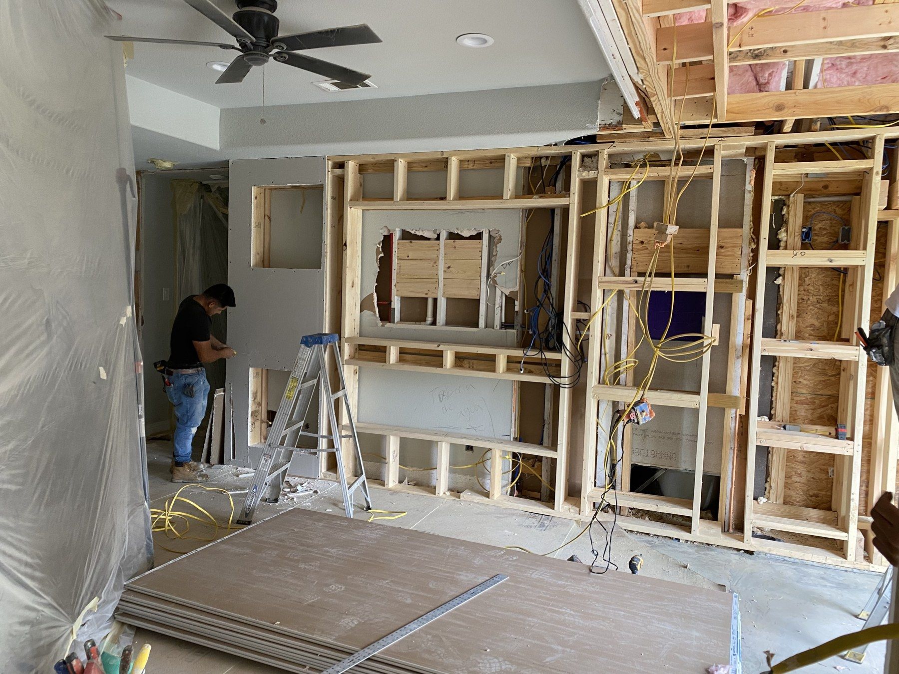 Living room media wall framed in wood with a worker on site