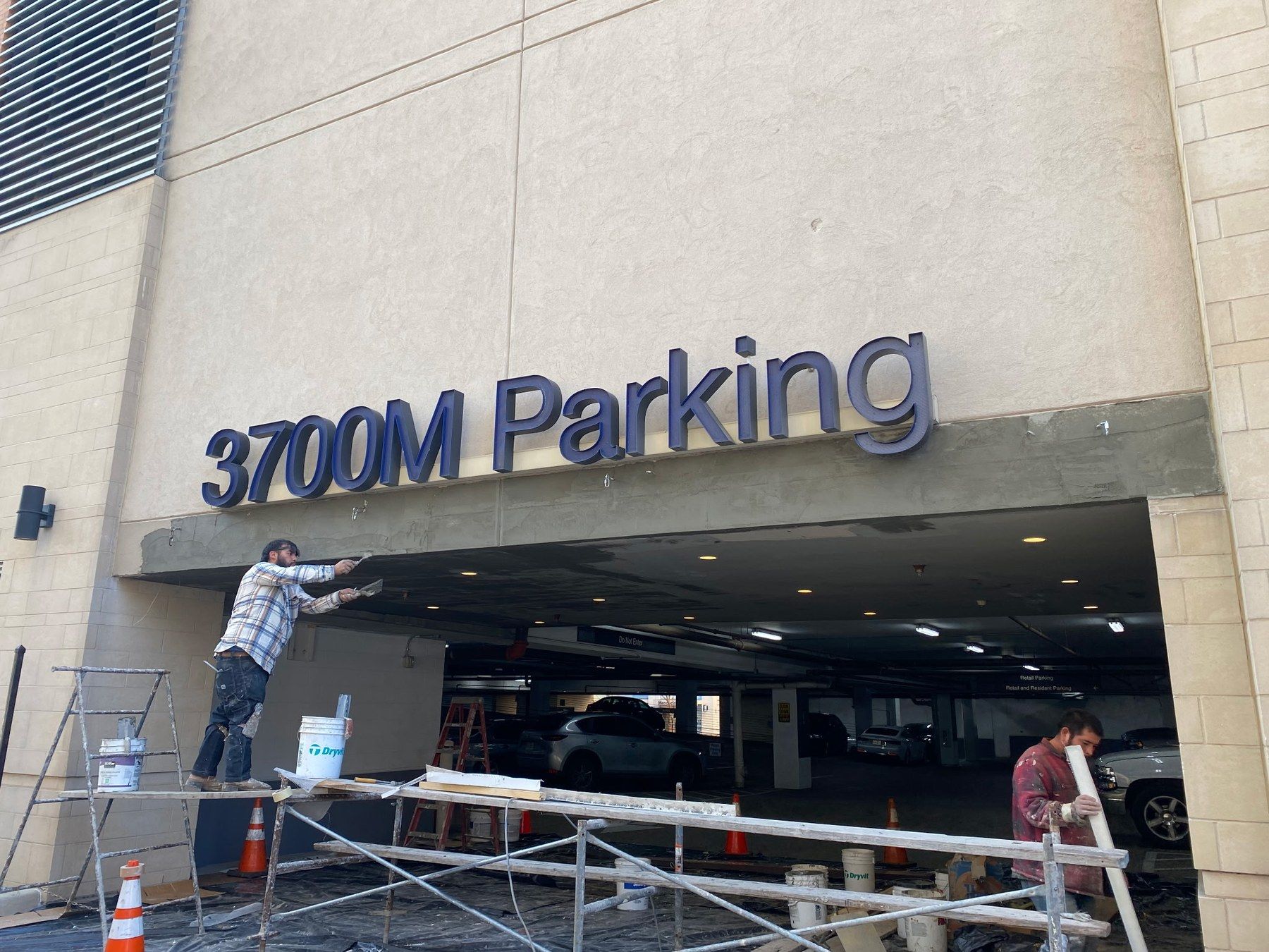 EJ1 crew on scaffolding repairing stucco at the 3700M parking garage entrance