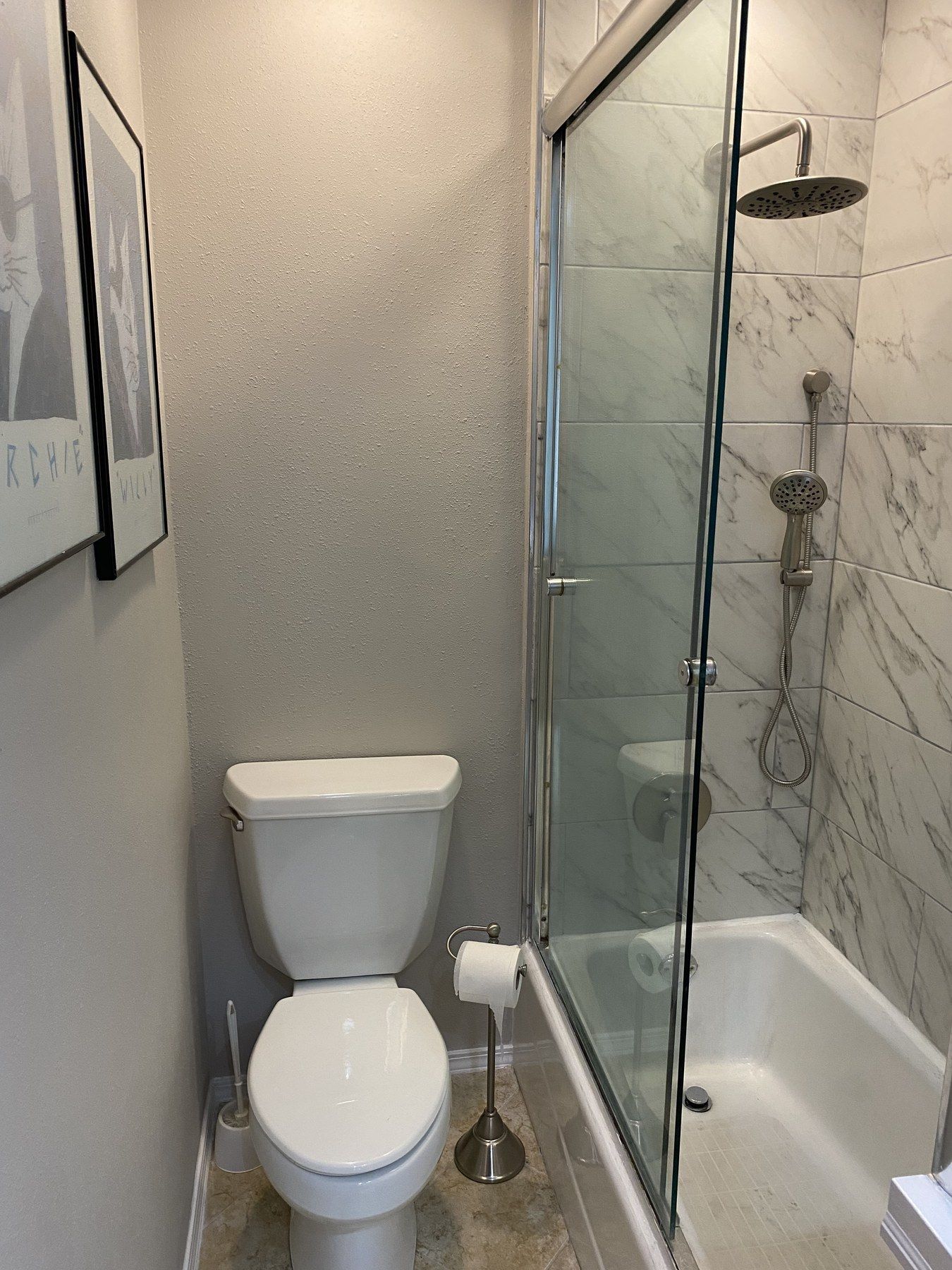 Hall bathroom with a sliding glass door over the tub and marble-look wall tile
